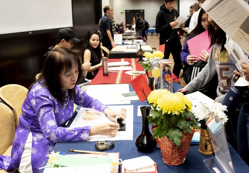 ASU Vietnamese language lecturer Thuy-Kim Le writes names in Vietnamese ink calligraphy for visiting students at the ASU Language Fair.