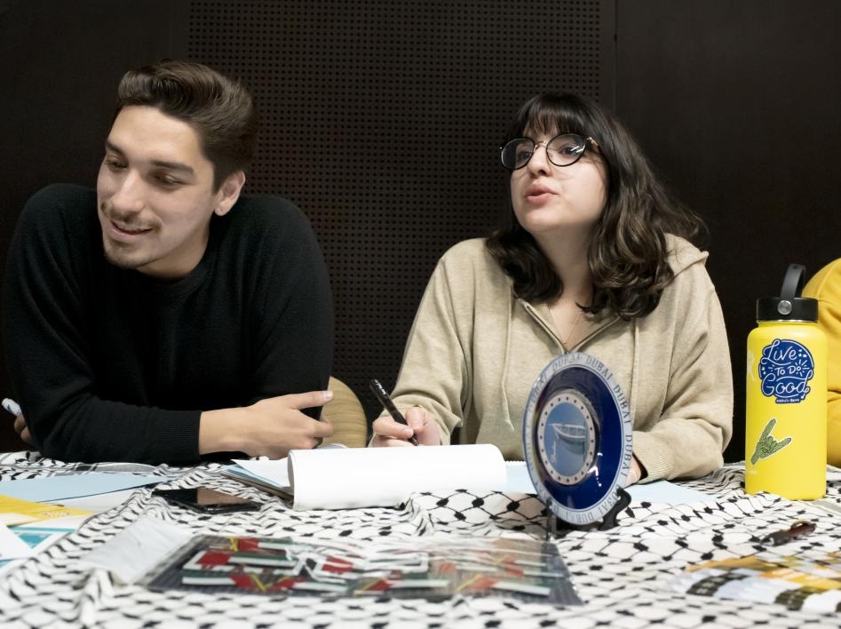 ASU students Lermon Montoya and Evanna Rouhani volunteer at the Arabic language table, writing in Arabic and answering program questions for visiting high school students.