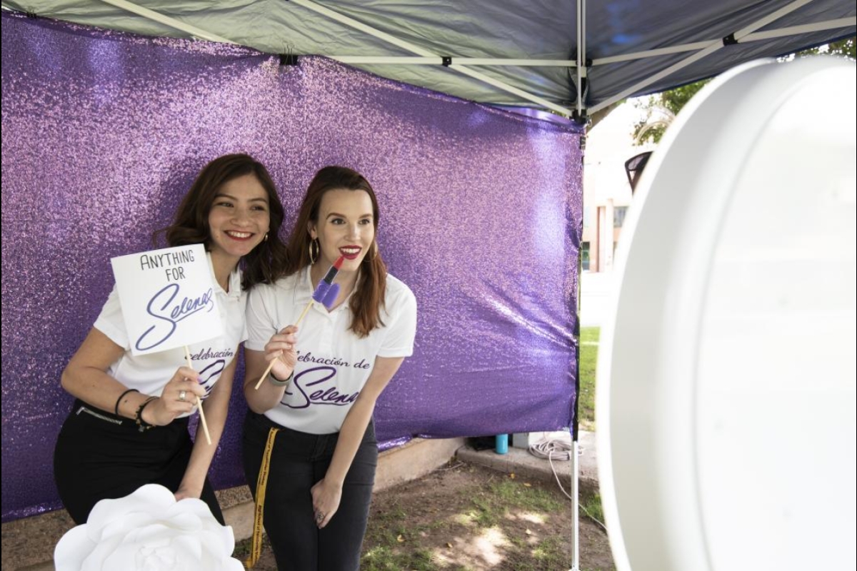 Christina Molidor, assistant to the director at the School of Transborder Studies, and Adilenne Diaz Hernandez, an administrative associate in the school, pose with Selena memorabilia in a photo booth at the event.