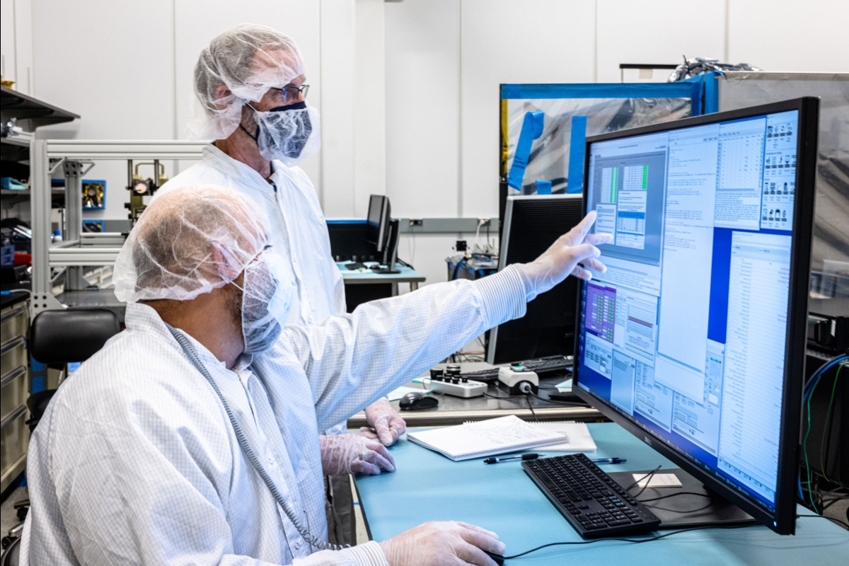 Men in lab coats point at a computer screen