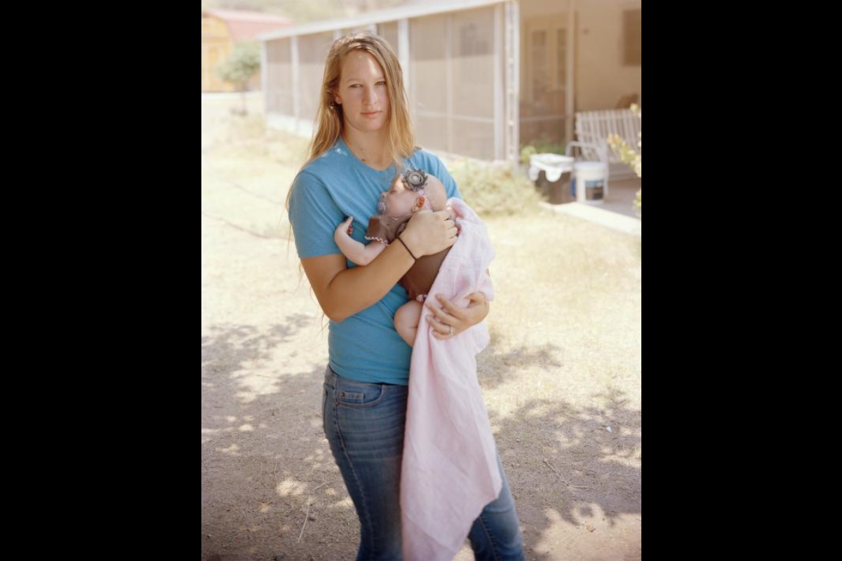 Photograph by Pam Golden shows a blonde woman holding a baby.