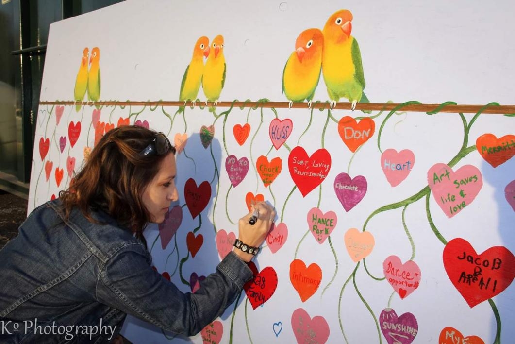 Kira signing a painted heart among others on a colorful mural