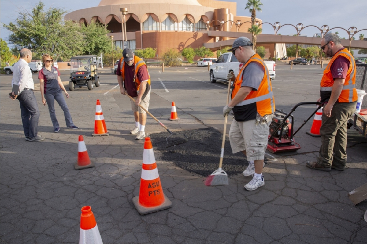 Workers apply AirDuo to patch an asphalt parking lot.