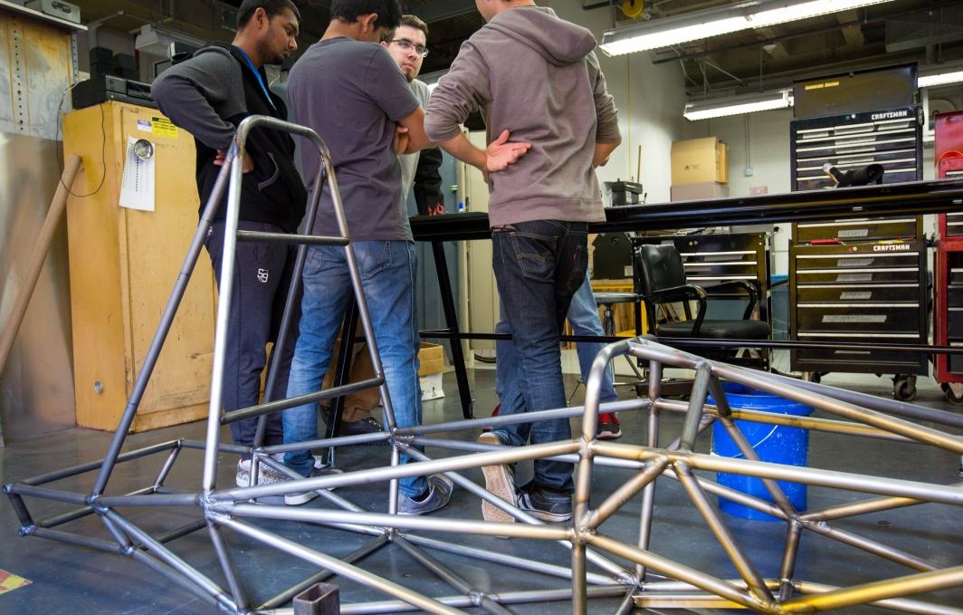 Formula SAE students with the car's chassis.