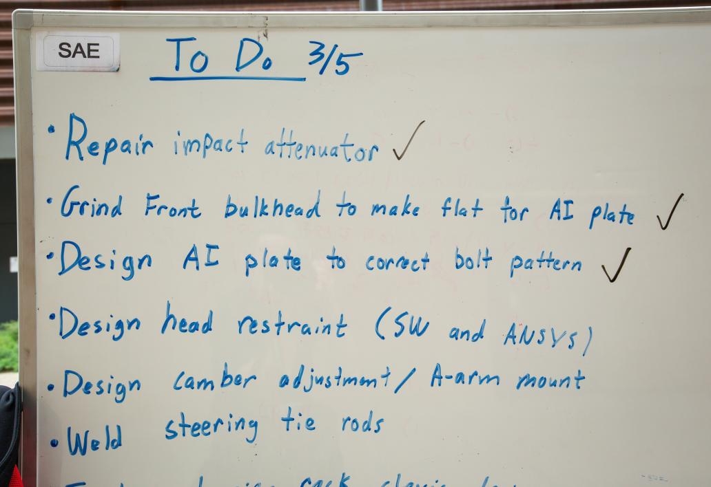 A to-do list on a whiteboard in the Formula SAE race car workshop.
