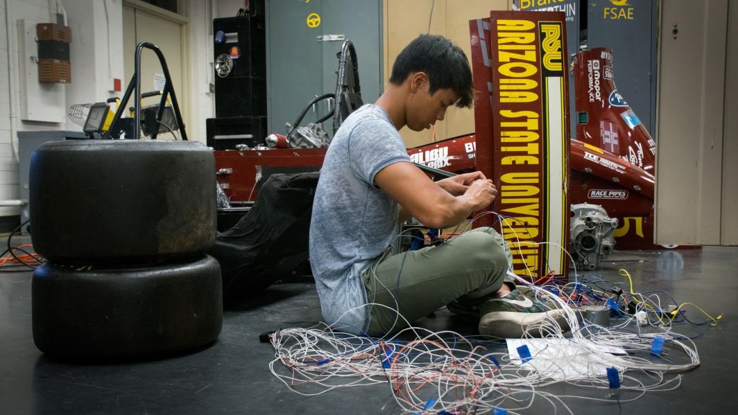 ASU student Gavin Charoenmin works on a wiring harness for the SAE race car