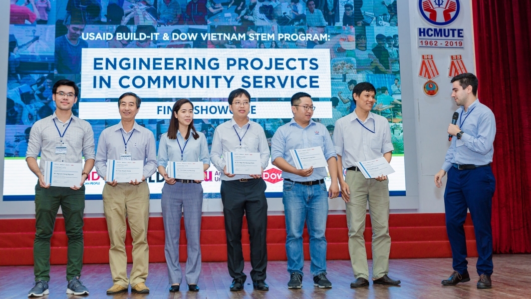 Group of people standing on a stage holding certificates.