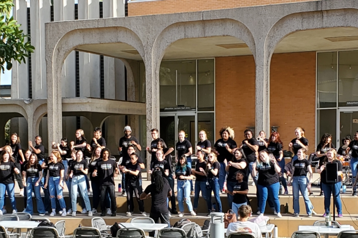Members of a choir standing outside of a building and singing.