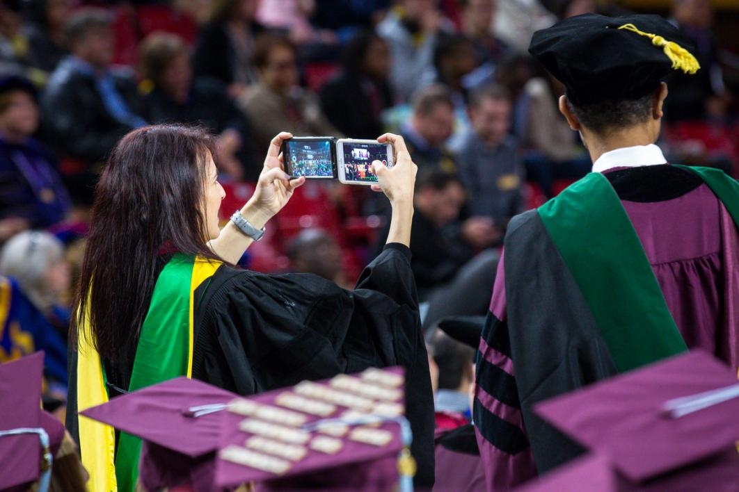 Woman uses two smart phones at graduation.