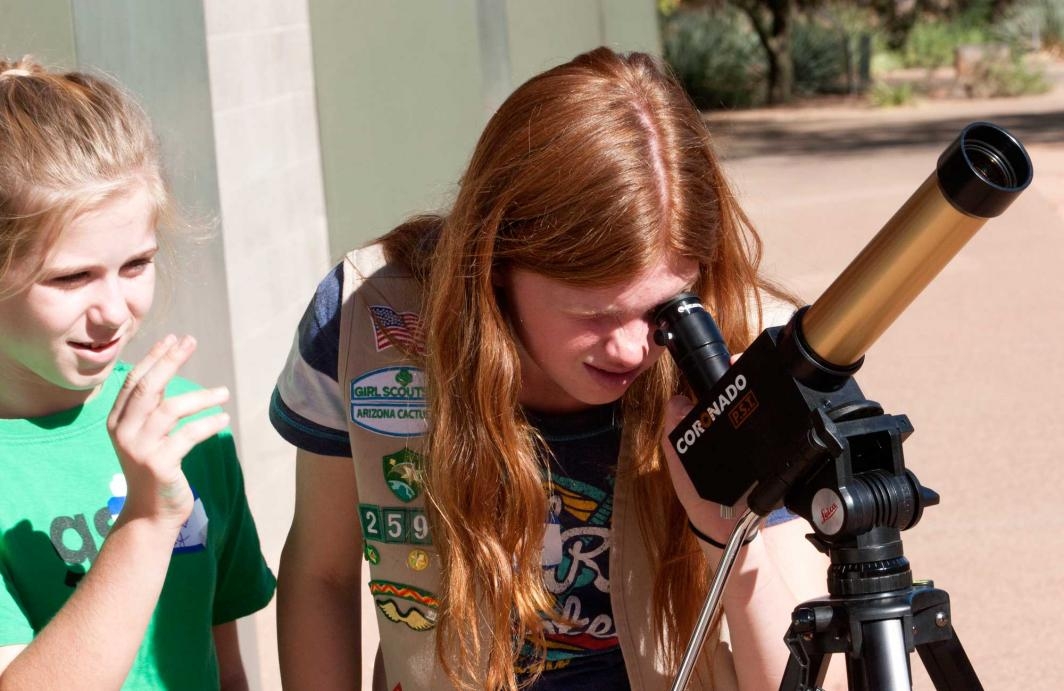 Scout gives pointers to friend as she looks at the sun through a telescope at ASU Polytechnic campus