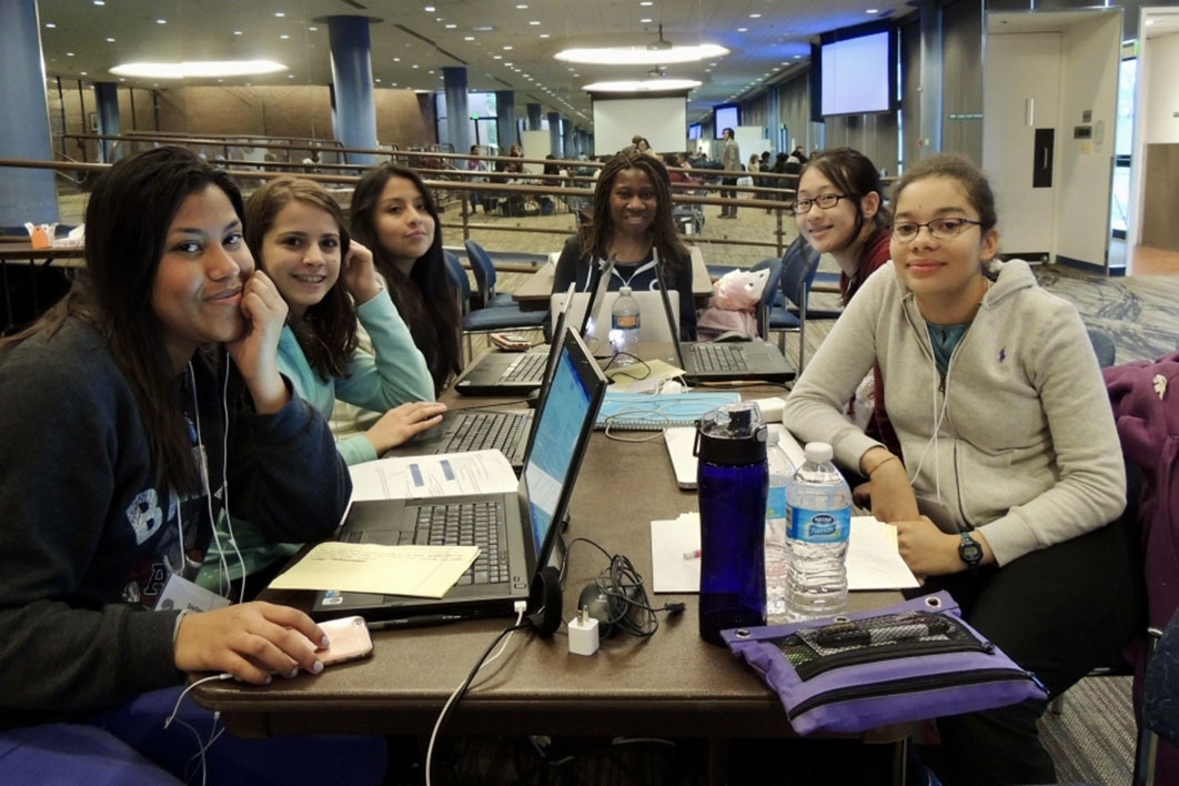 Group of girls gather around computers during a Hackathon in 2016