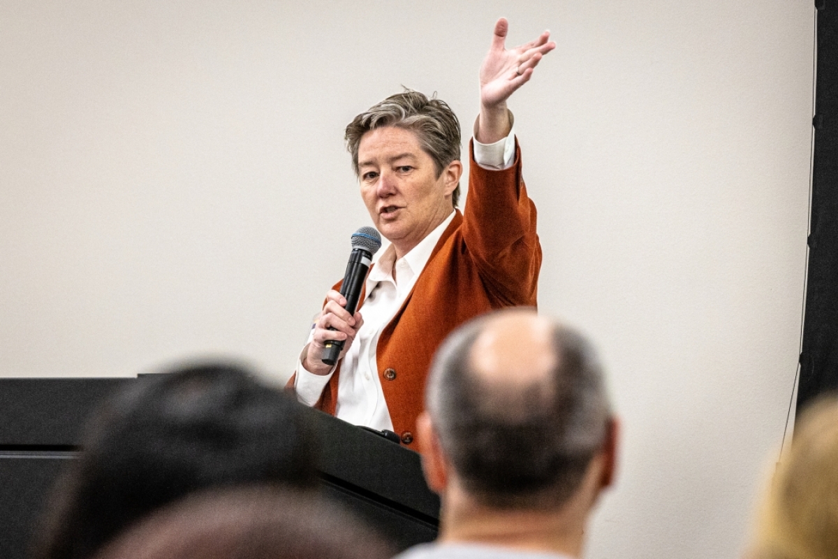 Woman speaking to a crowd with a microphone.