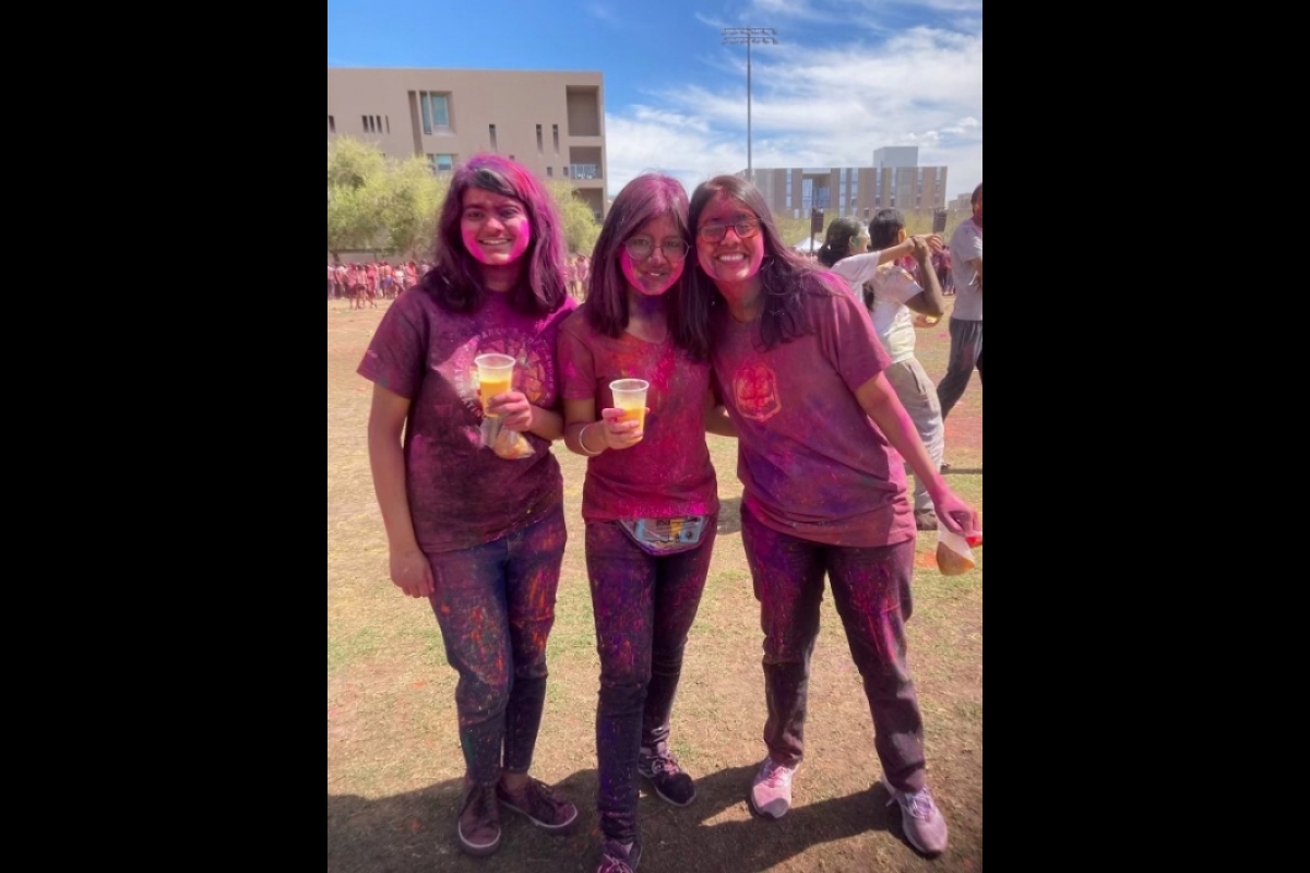 Three students covered in pink powder pose for a photo.