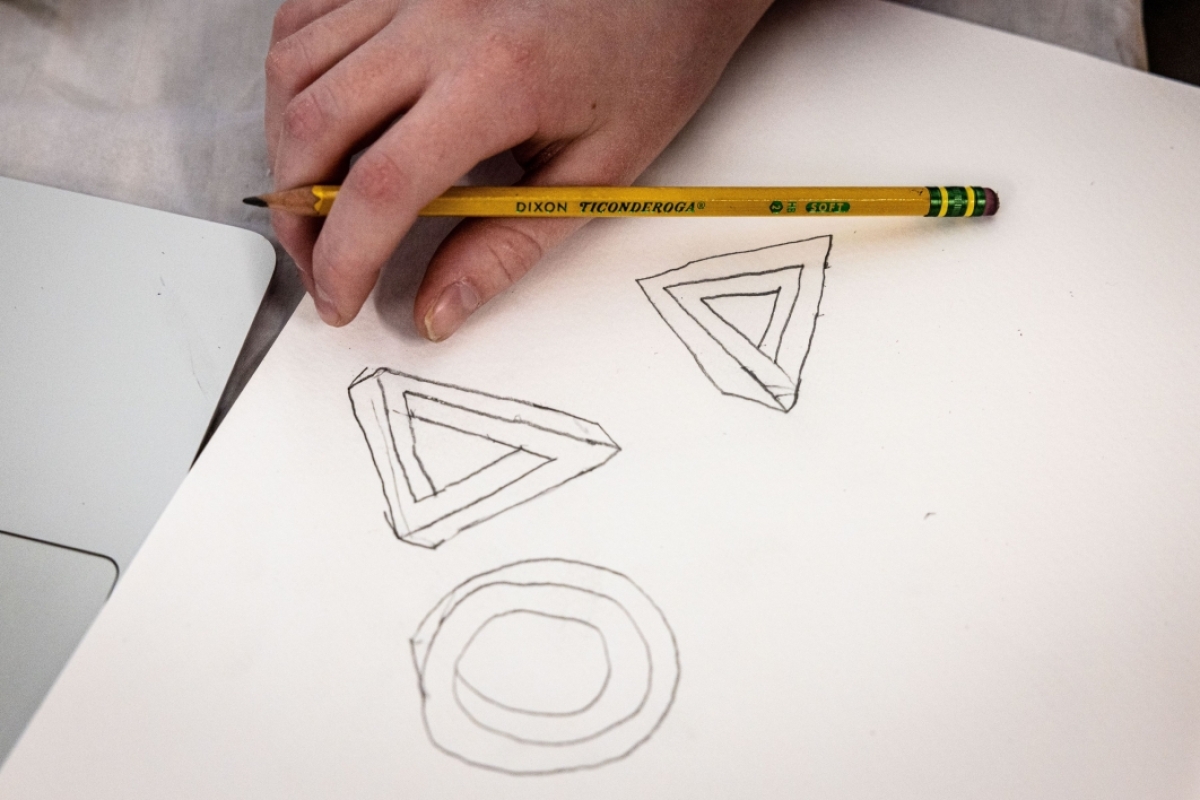 Close-up of a hand drawing geometric shapes.