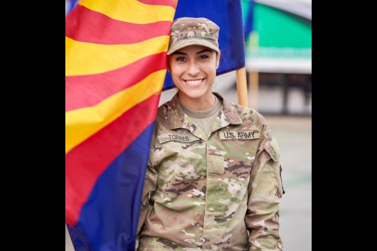 ASU Army ROTC Cadet Ruby Torres in Army fatigues next to the Arizona state flag.