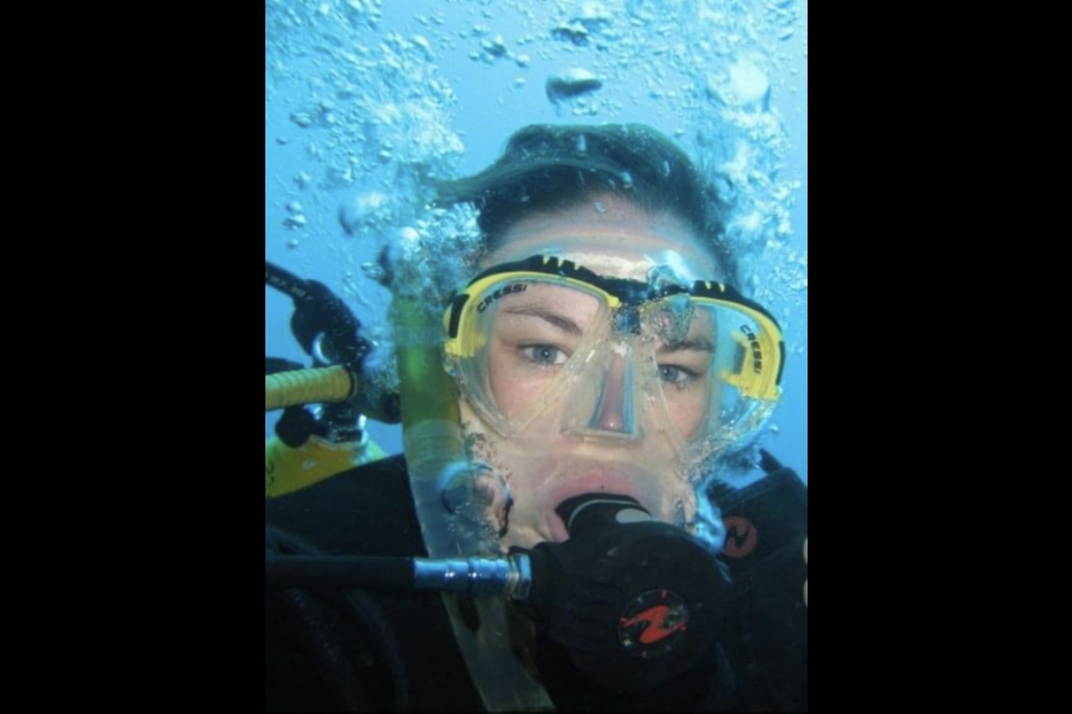 Woman wearing goggles and scuba gear under water.