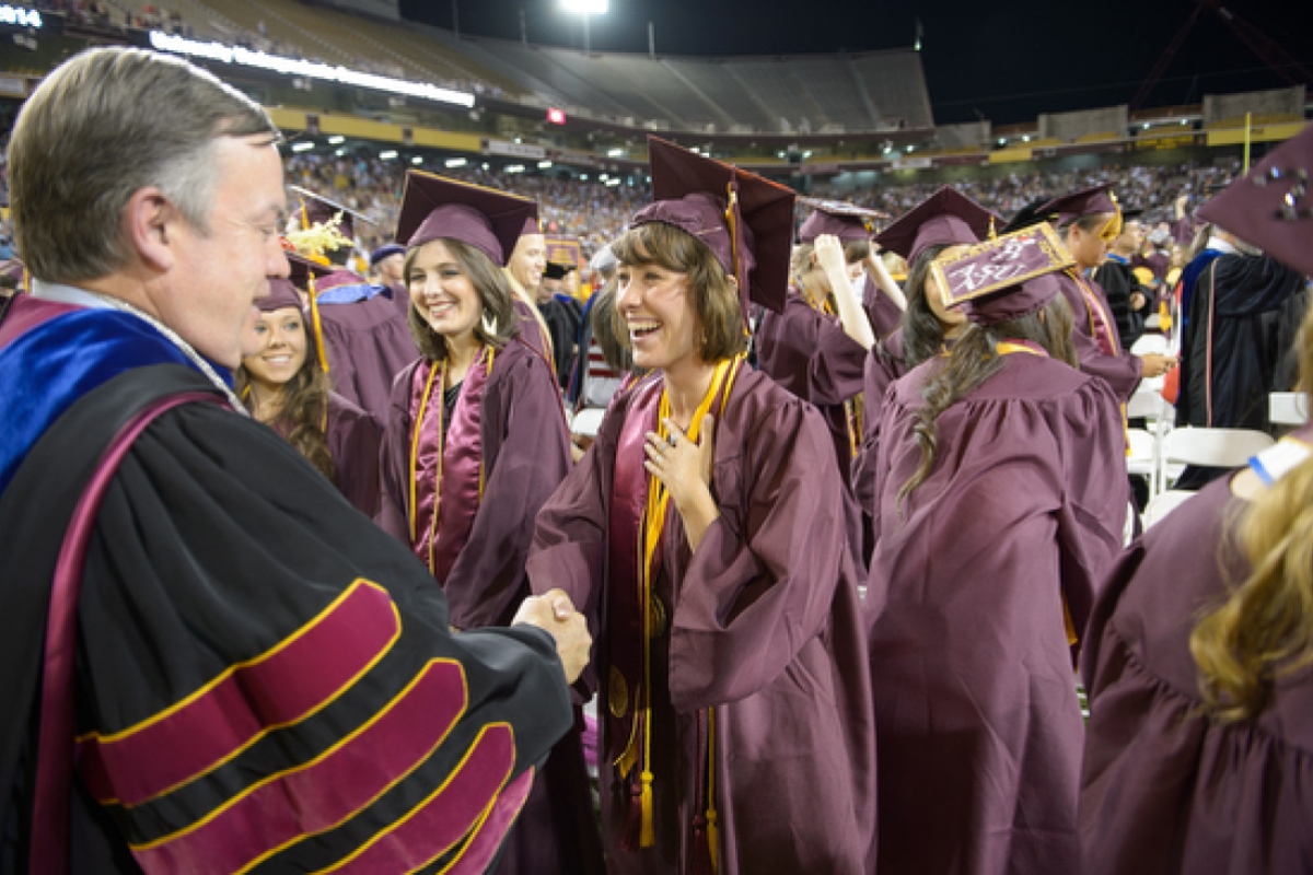 graduate shakes hands with President Crow