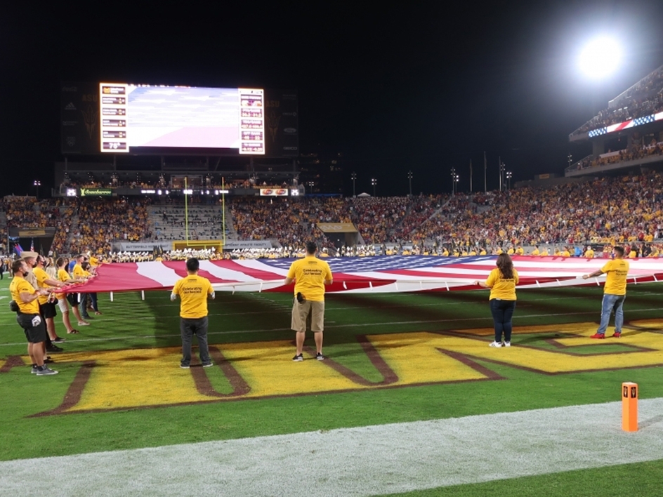 People holding giant American flag on football field
