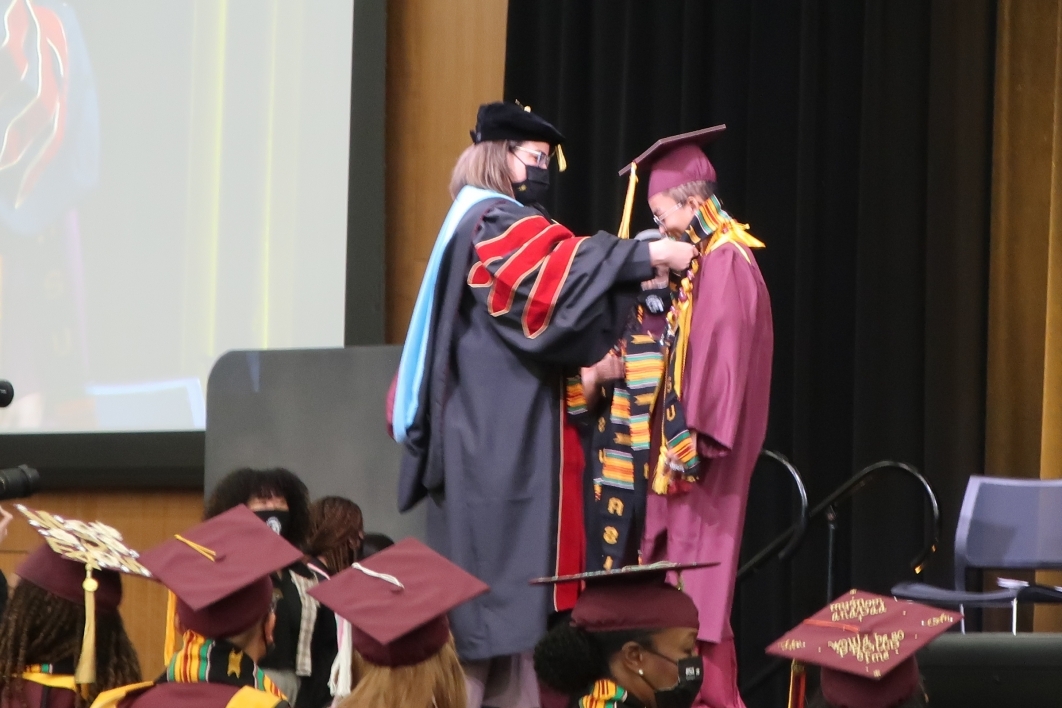 Dean of Students Cassandra Aska presents an ASU graduate with a stole at the Black African Convocation.