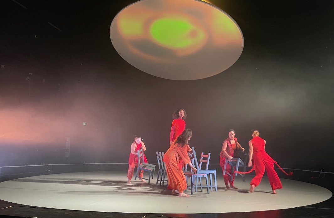 Performers dressed in red on a circular stage.