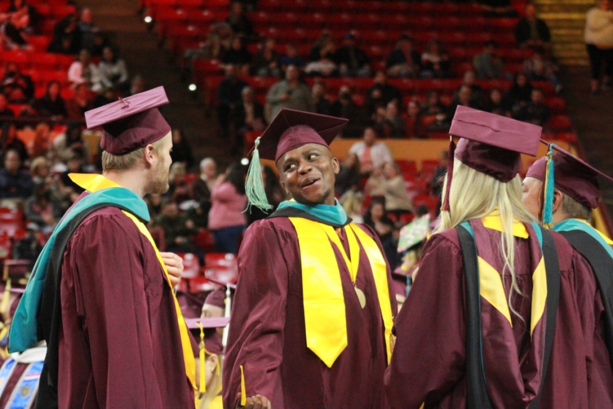 Graduates of ASU's Watts College of Public Service and Community Solutions wear graduation regalia and stand at their graduation ceremony.