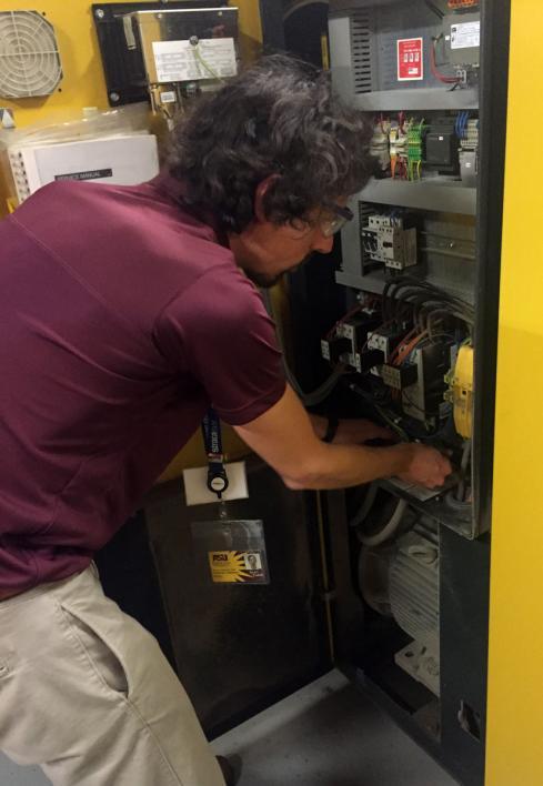 This photo shows ASU IAC student lead and mechanical engineering doctoral candidate Nicholas Fette examining a data logger on an HVAC system.