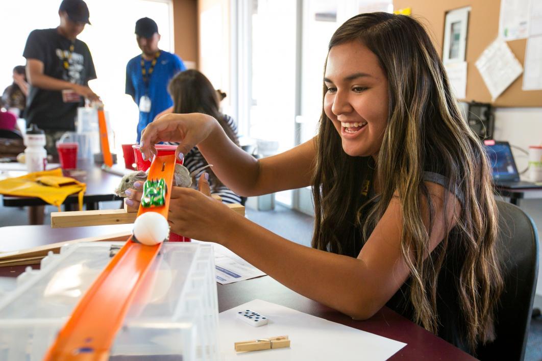 A student plays with a chain-reaction machine at Inspire camp.
