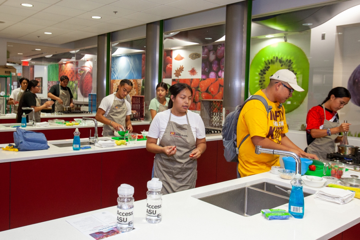 Native high school students wearing aprons and preparing food in a kitchen classroom.