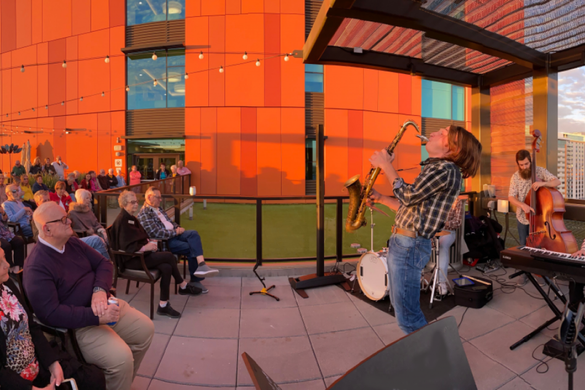 Student playing the saxophone in front of an audience on a rooftop.