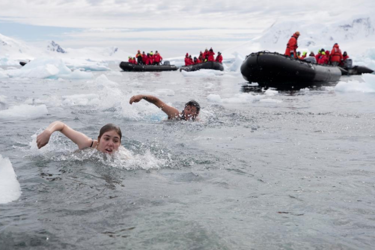 Two students swimming in Antarctica amidst doing a polar plunge