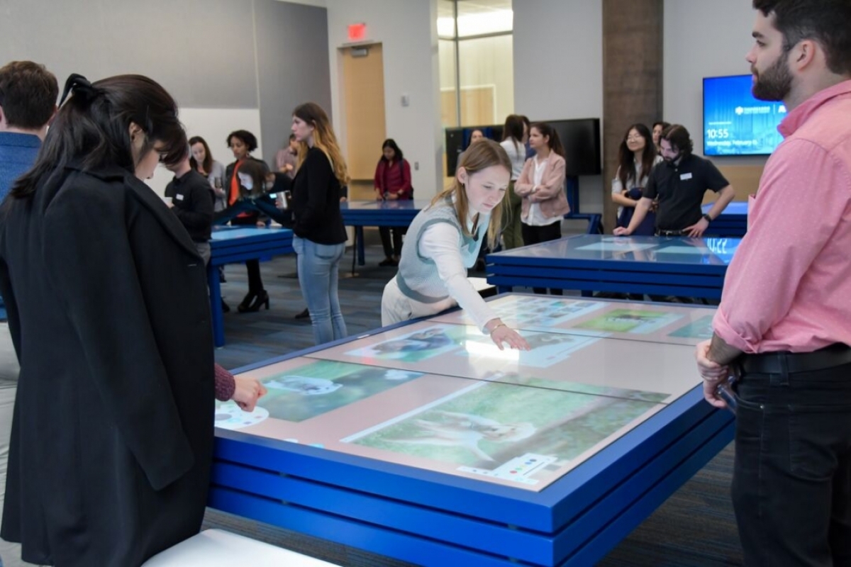Attendees shown interacting with the collaboration tables.