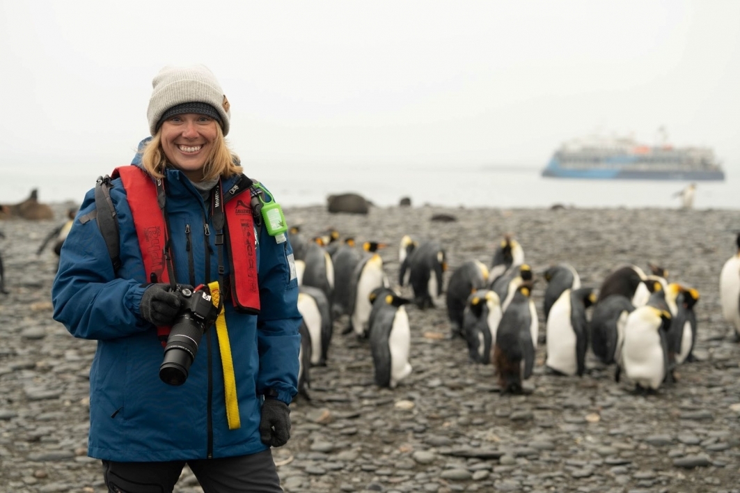 Photo of Lauren Richards standing in front of a group of penguins.