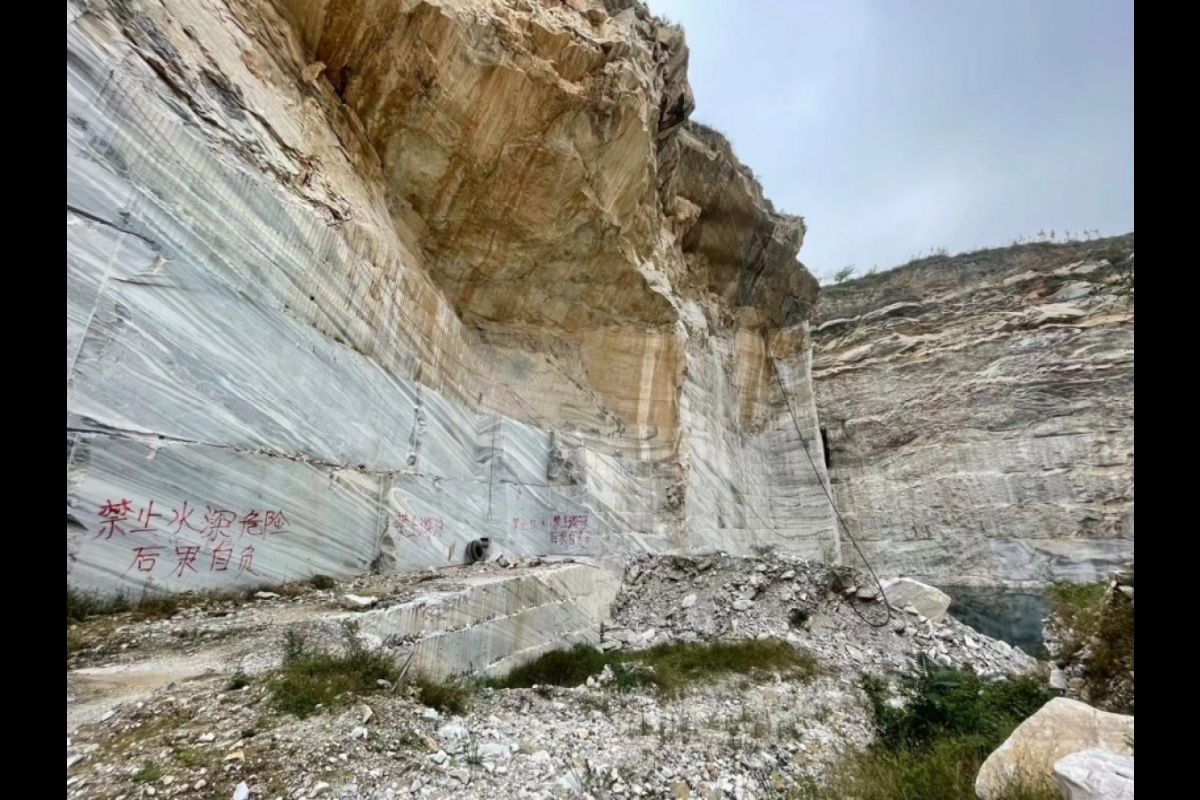 Photo of marble mines in China. Looks like a mountain side with Chinese writing on the stones.