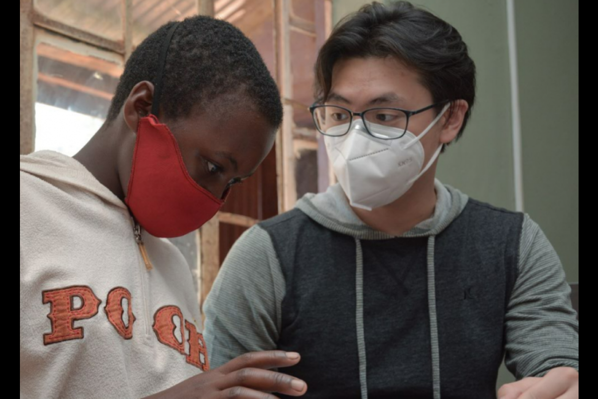 Student Michael Li (right) working with community member in Mukono