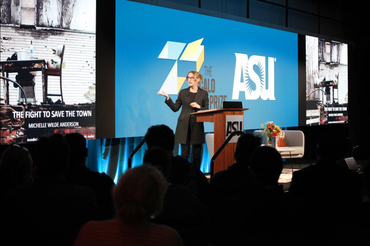 A woman stands behind a podium on stage with an ASU sign behind her.