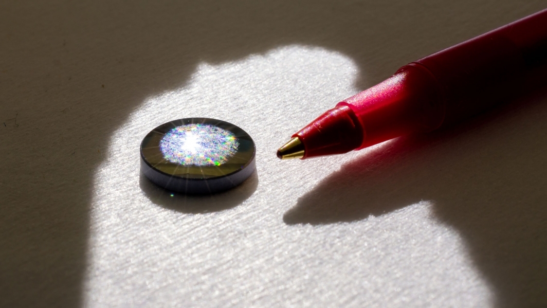 A silicon lens is pictured with a ballpoint pen for scale.