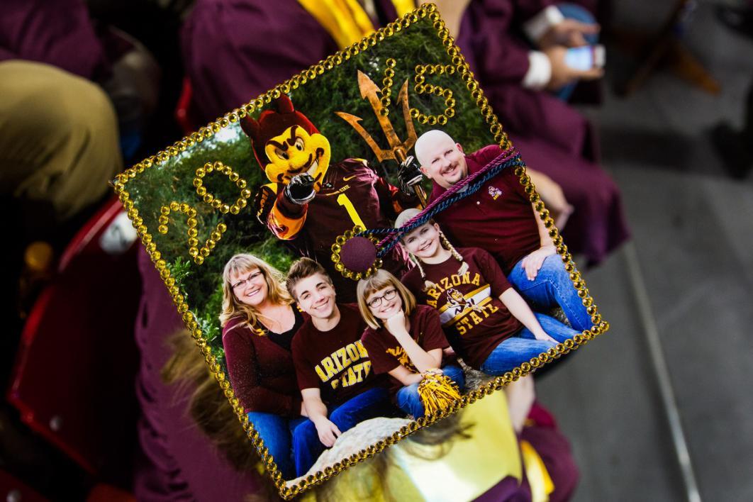 A graduation cap has a family photo with all members wearing maroon and gold
