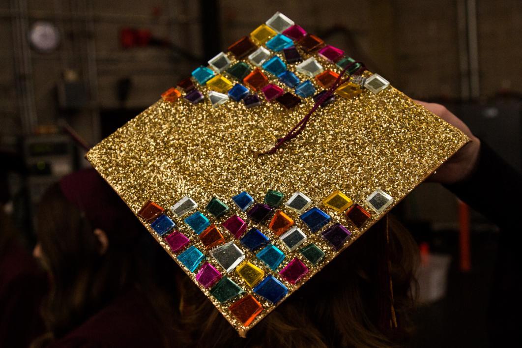 A graduation cap is covered in gold and jewels, resembling a prettier tetris board