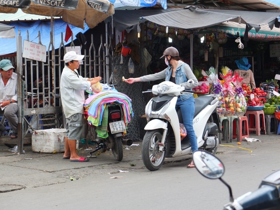 A person on a motorbike stops to buy something from a street vendor in Ho Chi Minh City.