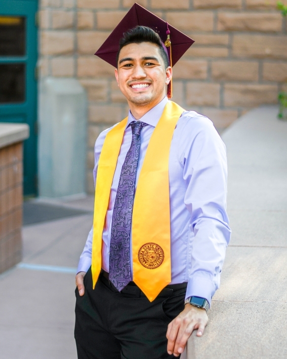 ASU College of Health Solutions graduate Adrian Muniz smiles while wearing his cap and graduation sash