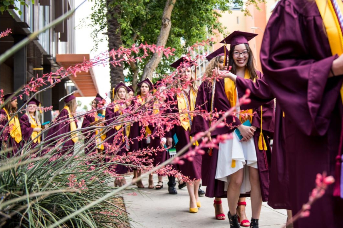 line of students walking in caps and gowns