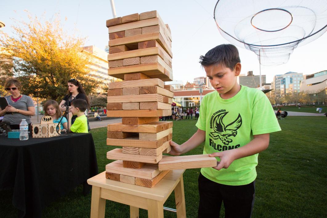 A boy plays with a set of giant Jenga pieces.