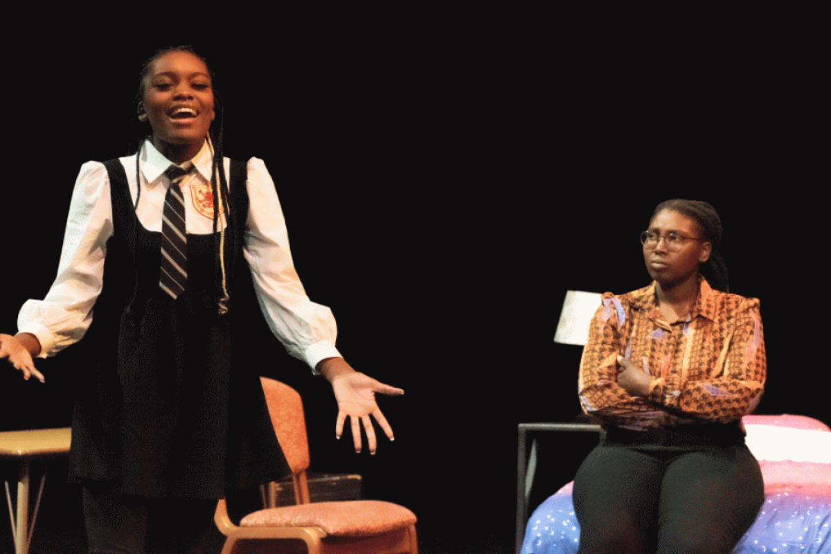 Two women on stage acting  in a play.
