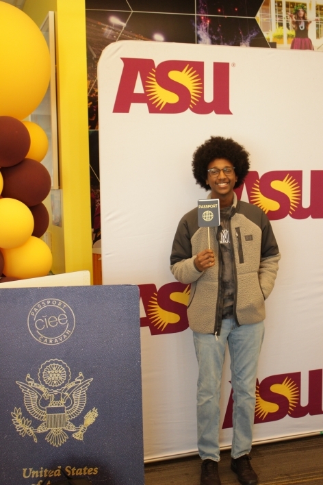 ASU student in front of a photo smiling after getting his first passport