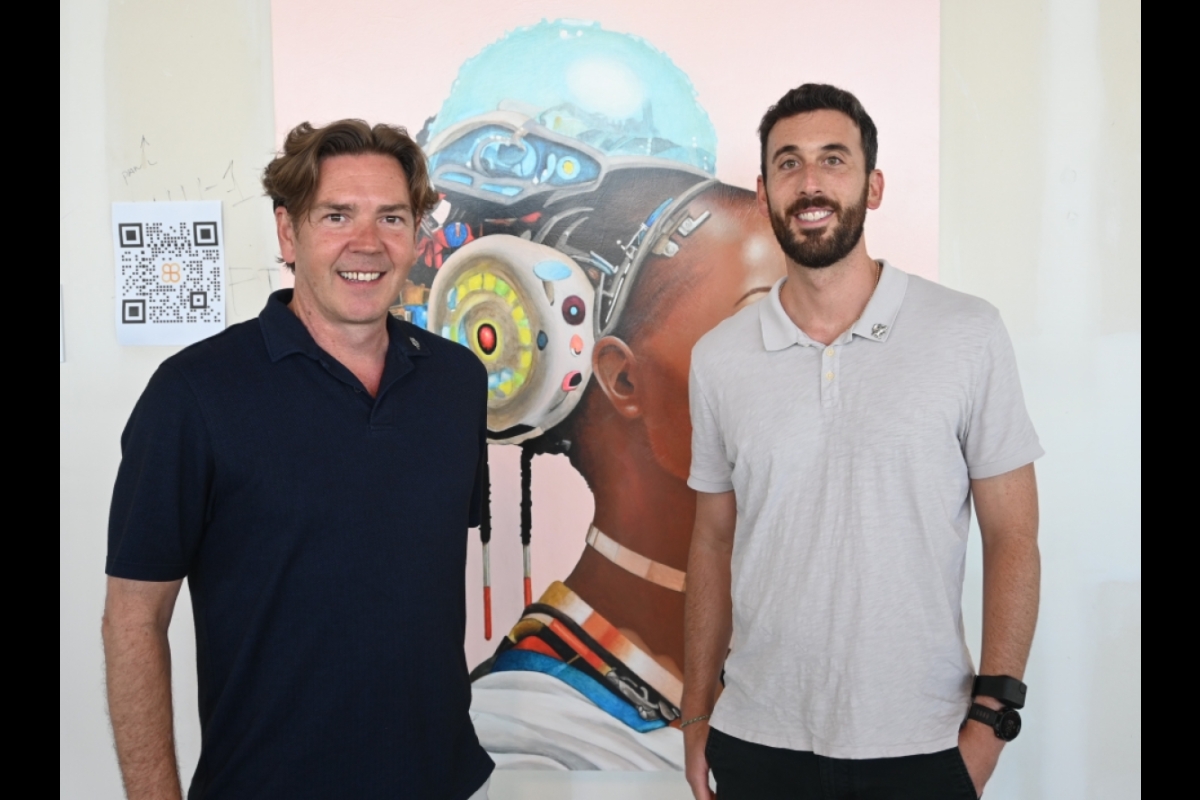Two men standing in front of an image of a person wearing a futuristic health device.
