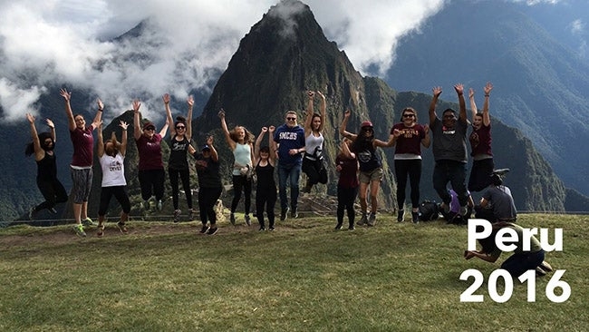 Students jump in the air as with Machu Picchu behind them