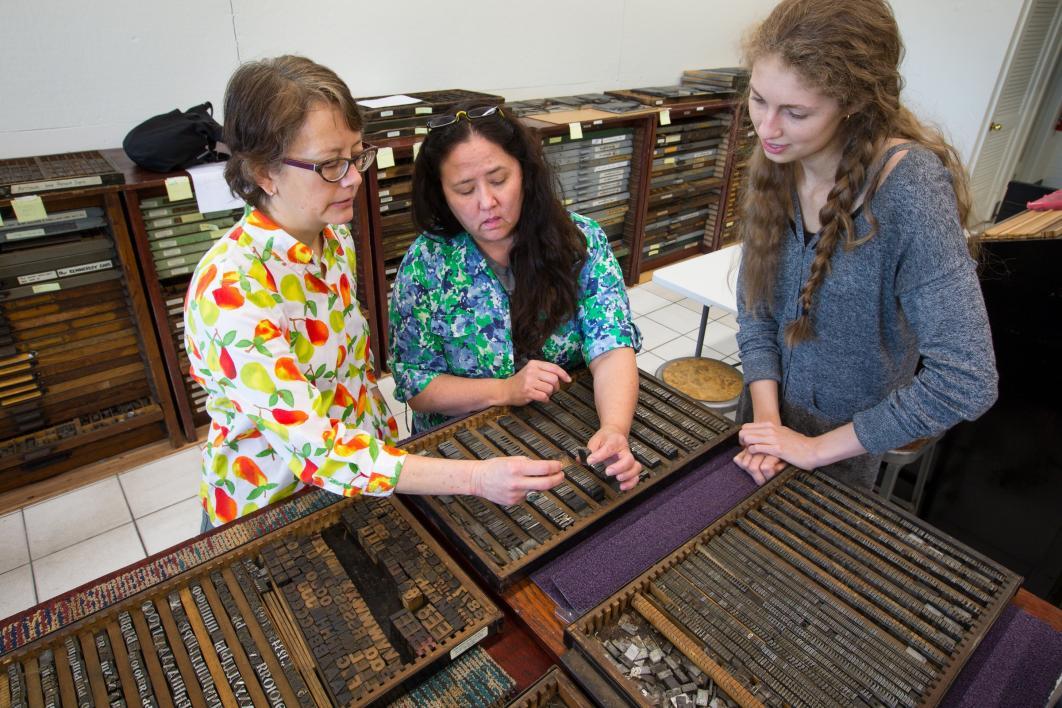 Three women examine print type.