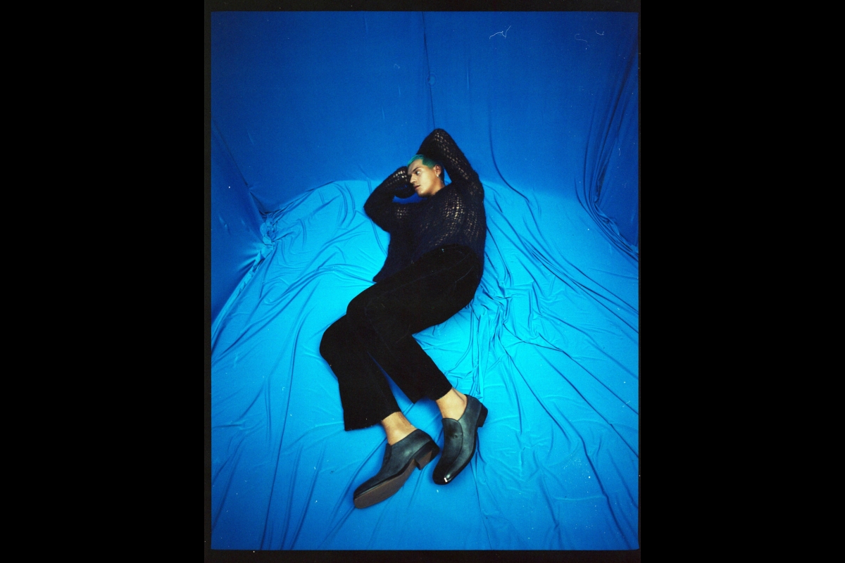 Omar Apollo laying on blue silk floor