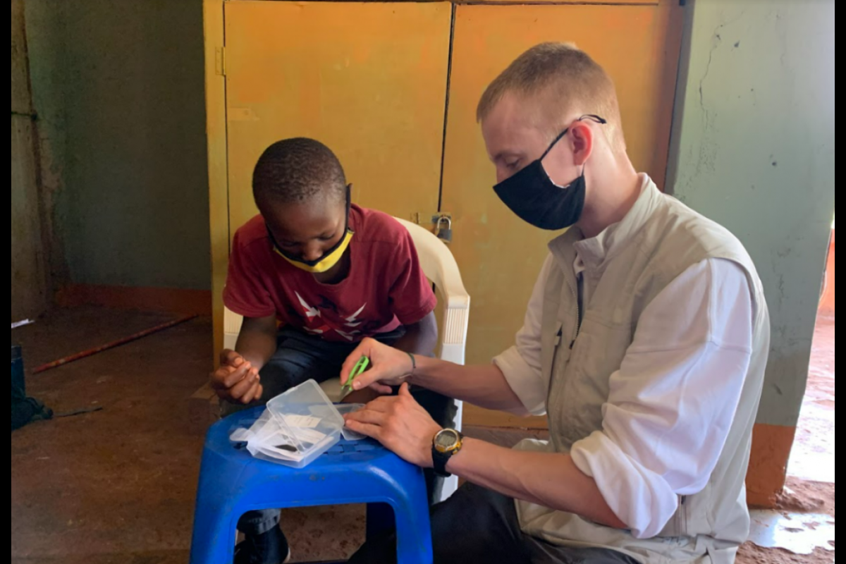 Student Benjamin Voller-Brown (right) teaching how to use the mosquito net patching kit