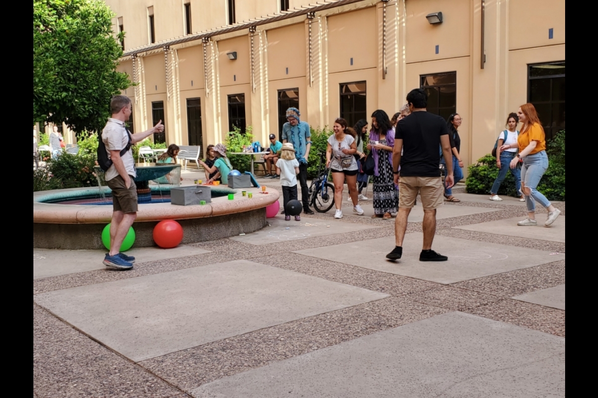 People interacting near a fountain oustide of a building.